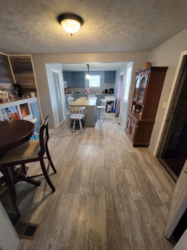 dining area with a textured ceiling and light hardwood / wood-style flooring