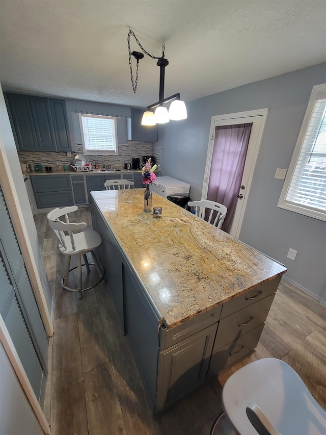 kitchen featuring backsplash, plenty of natural light, pendant lighting, and a center island