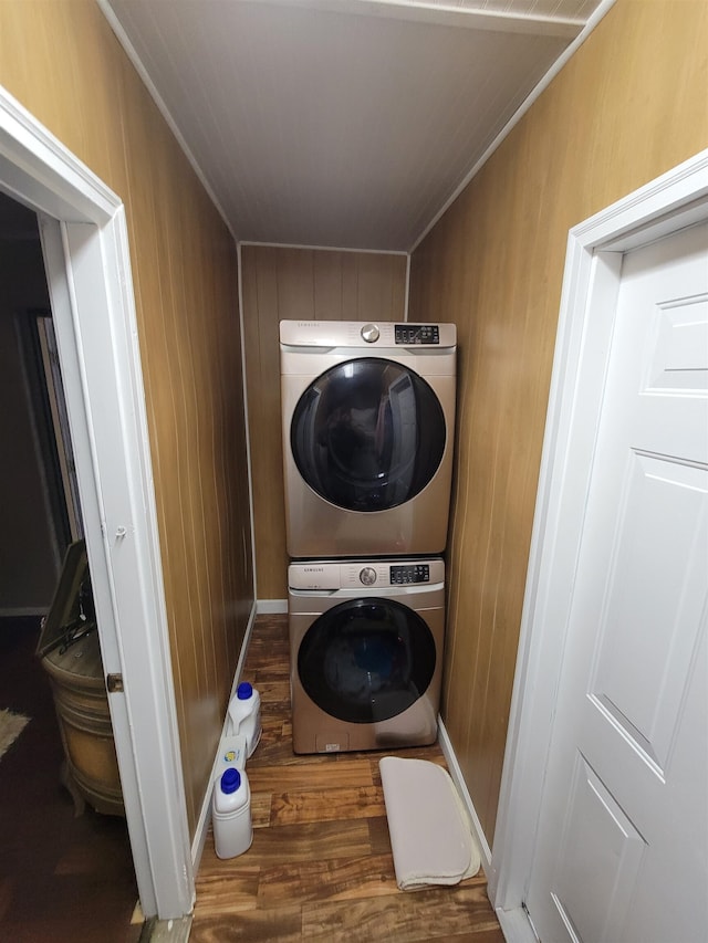 washroom featuring dark hardwood / wood-style flooring, wood walls, and stacked washer and dryer