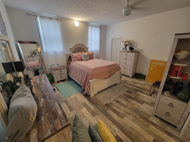 bedroom with hardwood / wood-style floors, ceiling fan, and a textured ceiling