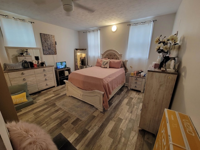 bedroom featuring dark wood-type flooring, ceiling fan, and a textured ceiling