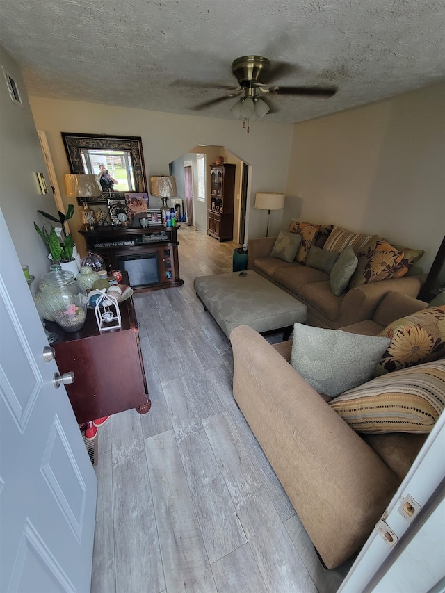 living room featuring hardwood / wood-style floors, ceiling fan, and a textured ceiling