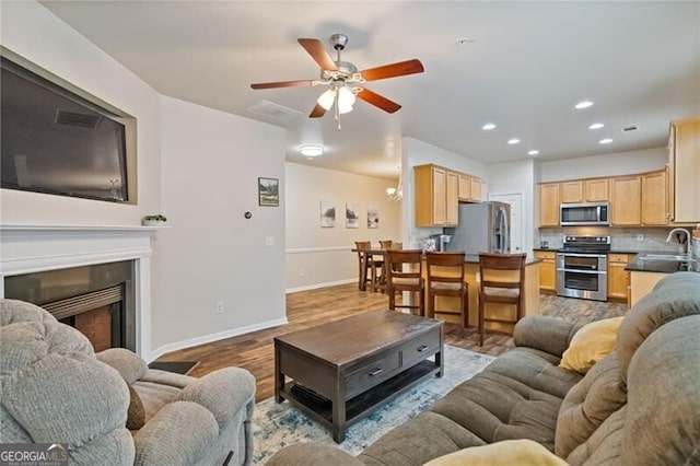 living room with hardwood / wood-style flooring, ceiling fan, and sink