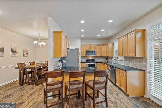 kitchen with an inviting chandelier, appliances with stainless steel finishes, sink, and hardwood / wood-style flooring