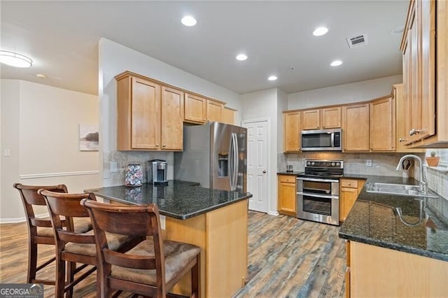 kitchen with light hardwood / wood-style floors, dark stone countertops, sink, and appliances with stainless steel finishes