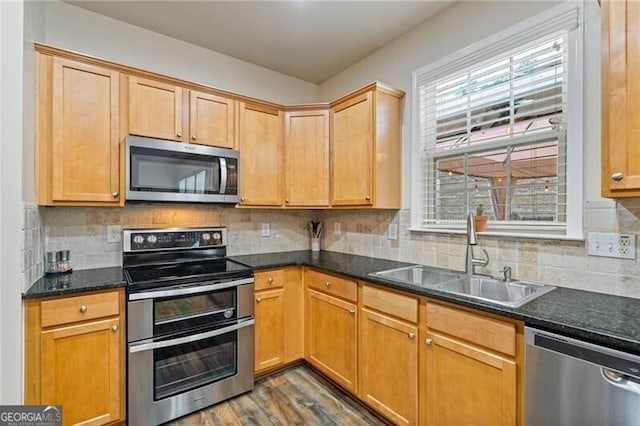 kitchen featuring stainless steel appliances, sink, dark stone counters, dark hardwood / wood-style floors, and backsplash