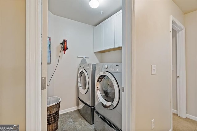 clothes washing area featuring cabinets and washer and dryer