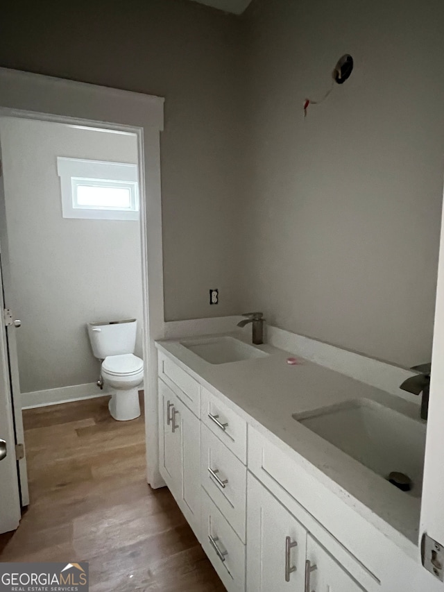 bathroom with hardwood / wood-style floors, vanity, and toilet