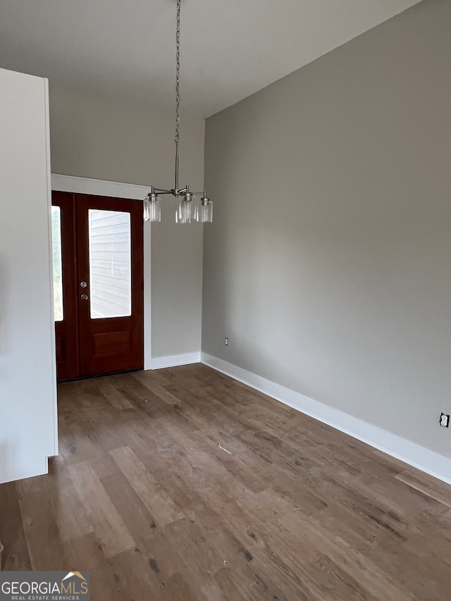 unfurnished dining area featuring a chandelier and hardwood / wood-style flooring