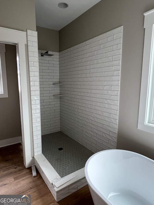 bathroom with hardwood / wood-style flooring and shower with separate bathtub