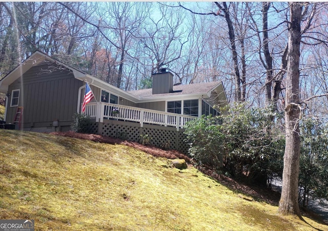 rear view of house featuring a yard, a sunroom, and a deck