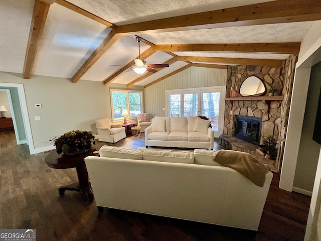 living room featuring vaulted ceiling with beams, a stone fireplace, ceiling fan, and dark wood-type flooring