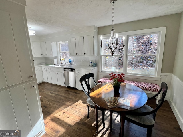 dining room with sink, breakfast area, dark hardwood / wood-style flooring, a textured ceiling, and a chandelier