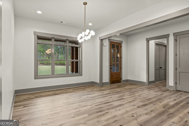 unfurnished dining area with hardwood / wood-style floors and a chandelier