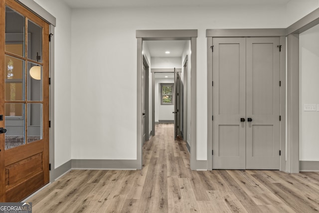 hallway with light wood-type flooring and a barn door