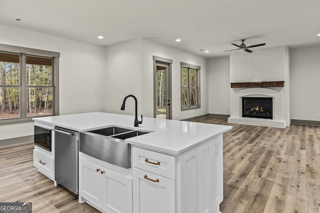 kitchen featuring plenty of natural light, white cabinetry, a center island with sink, and dishwasher