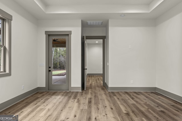 unfurnished room featuring a raised ceiling and light hardwood / wood-style flooring