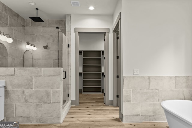 bathroom featuring tile walls, wood-type flooring, and independent shower and bath