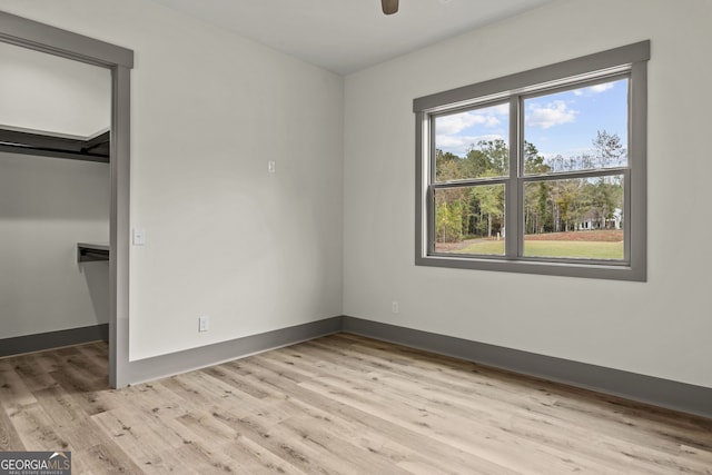 unfurnished bedroom featuring light hardwood / wood-style floors and a spacious closet