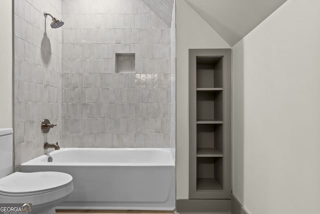 bathroom with toilet, tiled shower / bath, vaulted ceiling, and built in shelves