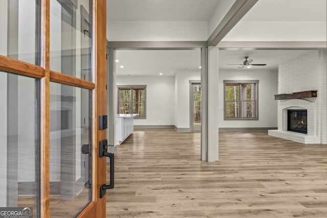 interior space featuring light hardwood / wood-style flooring, a fireplace, ceiling fan, and plenty of natural light