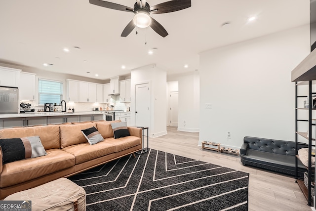 living room featuring sink, ceiling fan, and light wood-type flooring