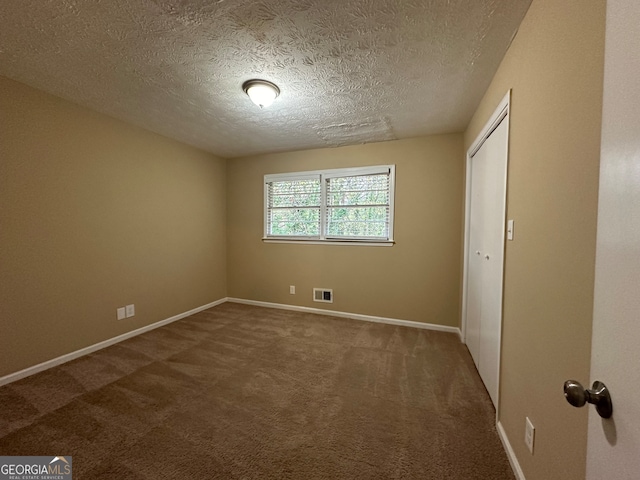 unfurnished bedroom with a textured ceiling, a closet, and carpet