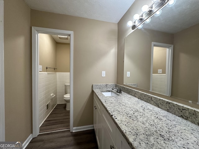 2929 Stratford Mill Rd, Lithonia, GA 30038 - bathroom featuring toilet, wood finished floors, tile walls, vanity, and wainscoting