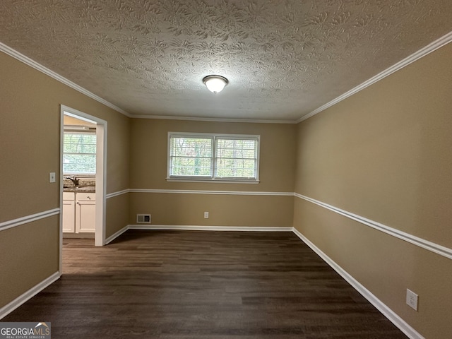 empty room featuring dark wood-type flooring, a textured ceiling, and crown molding