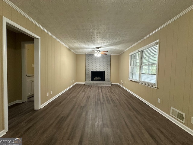 unfurnished living room with ornamental molding, a fireplace, a textured ceiling, dark wood-type flooring, and ceiling fan