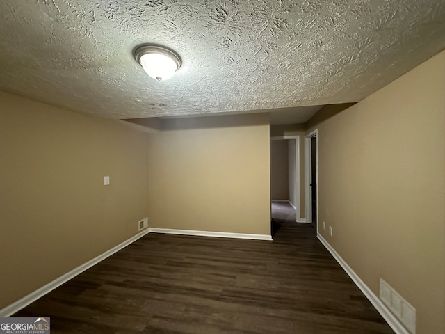 basement featuring dark wood-type flooring and a textured ceiling