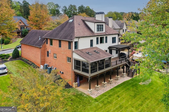 rear view of property featuring a sunroom, a yard, and a patio area