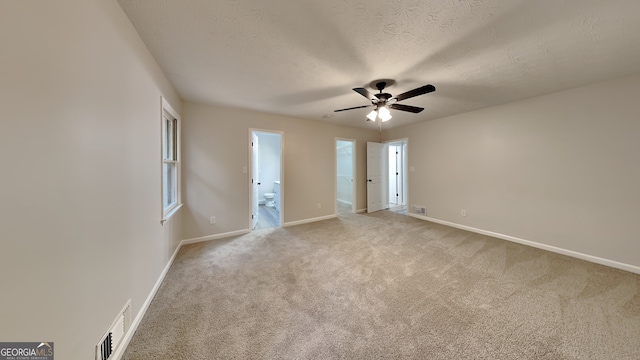 carpeted spare room with a textured ceiling, a healthy amount of sunlight, and ceiling fan