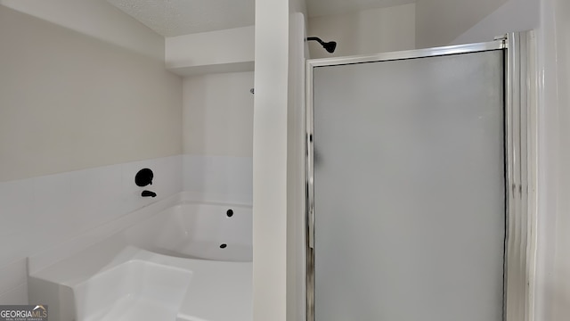 bathroom with a textured ceiling and shower with separate bathtub