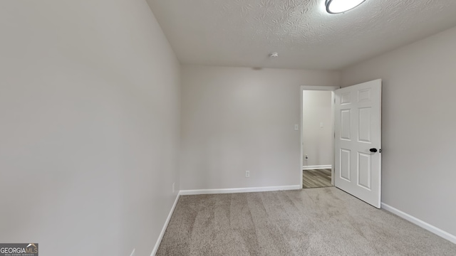 empty room with a textured ceiling and light colored carpet