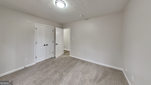 unfurnished room with light colored carpet and a textured ceiling