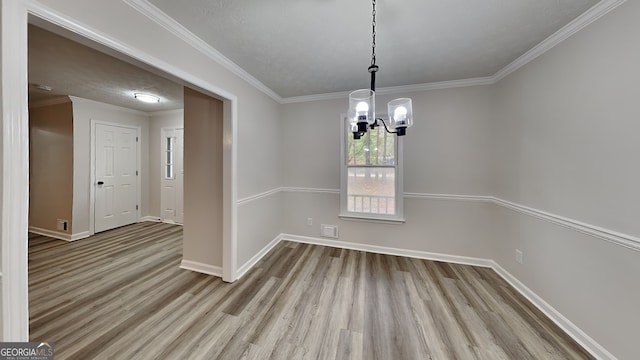 unfurnished dining area with an inviting chandelier, a textured ceiling, light hardwood / wood-style flooring, and ornamental molding