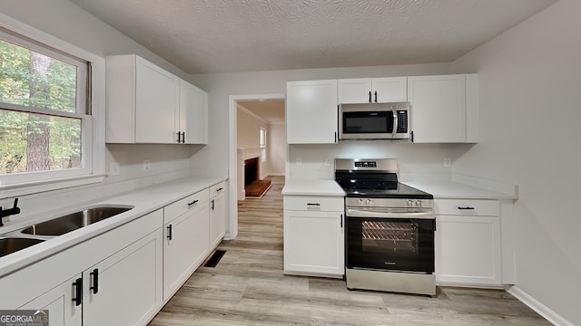 245 Southmoor Cir, Stockbridge, GA 30281 - kitchen with appliances with stainless steel finishes, light wood-type flooring, white cabinetry, light countertops, and a textured ceiling