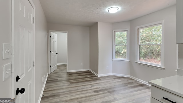 unfurnished room with light hardwood / wood-style flooring and a textured ceiling