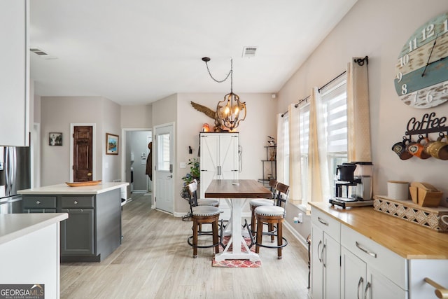 kitchen with light hardwood / wood-style floors, stainless steel refrigerator with ice dispenser, a center island, gray cabinets, and pendant lighting