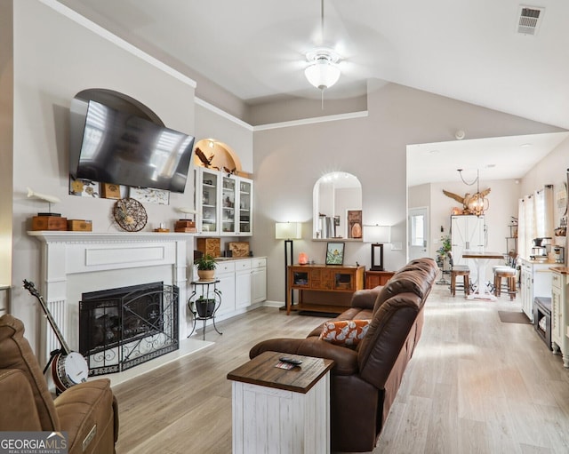 living room with ceiling fan with notable chandelier, light hardwood / wood-style flooring, and high vaulted ceiling