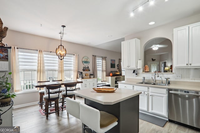 kitchen featuring sink, tasteful backsplash, stainless steel dishwasher, pendant lighting, and white cabinetry