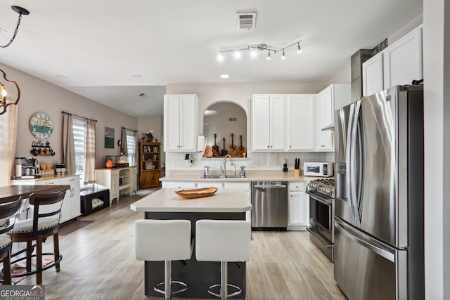 kitchen featuring light wood-type flooring, appliances with stainless steel finishes, sink, and a center island