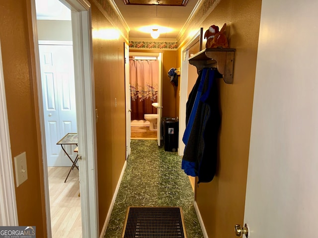 hallway with wood-type flooring and crown molding