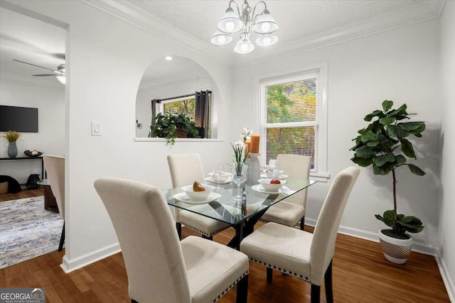 dining space featuring ceiling fan with notable chandelier, dark hardwood / wood-style floors, and crown molding