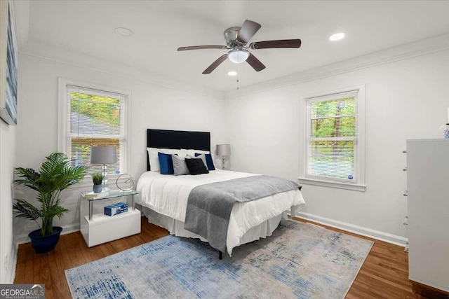 bedroom with ceiling fan, multiple windows, dark hardwood / wood-style flooring, and crown molding