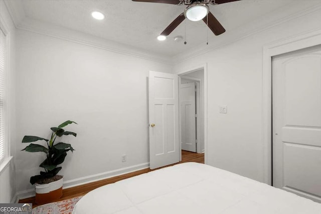 bedroom with ornamental molding, a closet, wood-type flooring, and ceiling fan