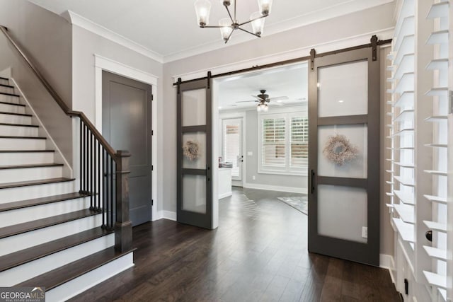 entryway with dark hardwood / wood-style flooring, a barn door, ornamental molding, and ceiling fan with notable chandelier