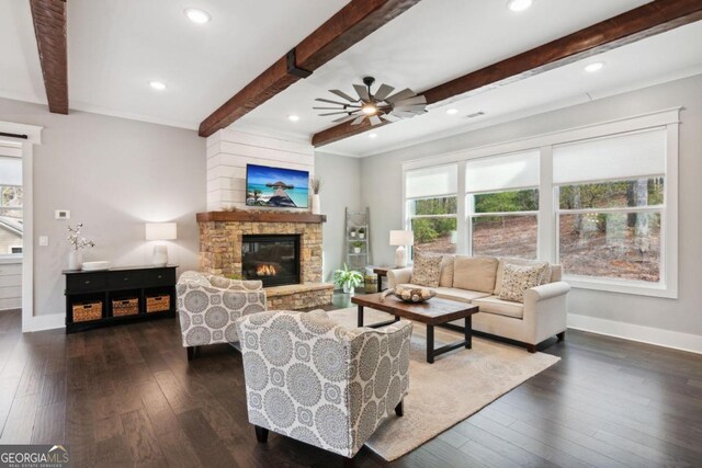 living room with dark hardwood / wood-style flooring, beamed ceiling, a stone fireplace, and ceiling fan