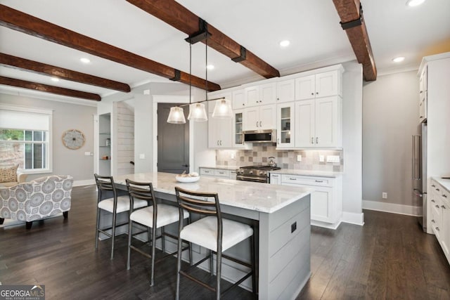 kitchen with a kitchen island, appliances with stainless steel finishes, dark hardwood / wood-style floors, hanging light fixtures, and white cabinets